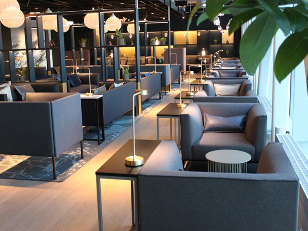 Moderne og elegant lounge med komfortable grå sofaar, små bordlampar, og dekorative element, designa for avslapping og sosial interaksjon.