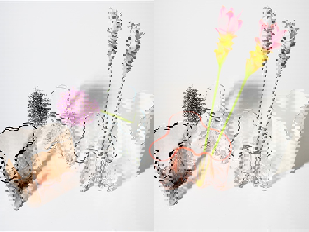 Samling av glassvaser med unike former og varierende farger, med rosa og lilla blomster, vist på en hvit bakgrunn