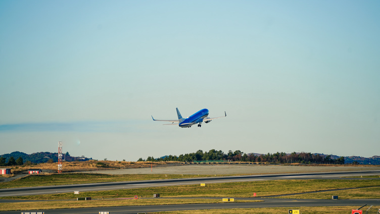 Airplane taking off from the runway at the airport, clear blue sky in the background.