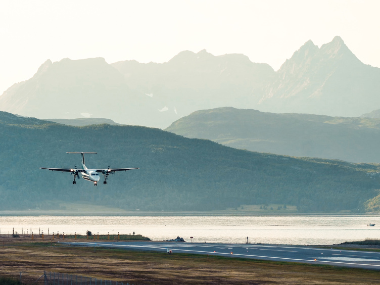 Fly lander på Senja flyplass med majestetiske fjell i bakgrunnen, Norge.