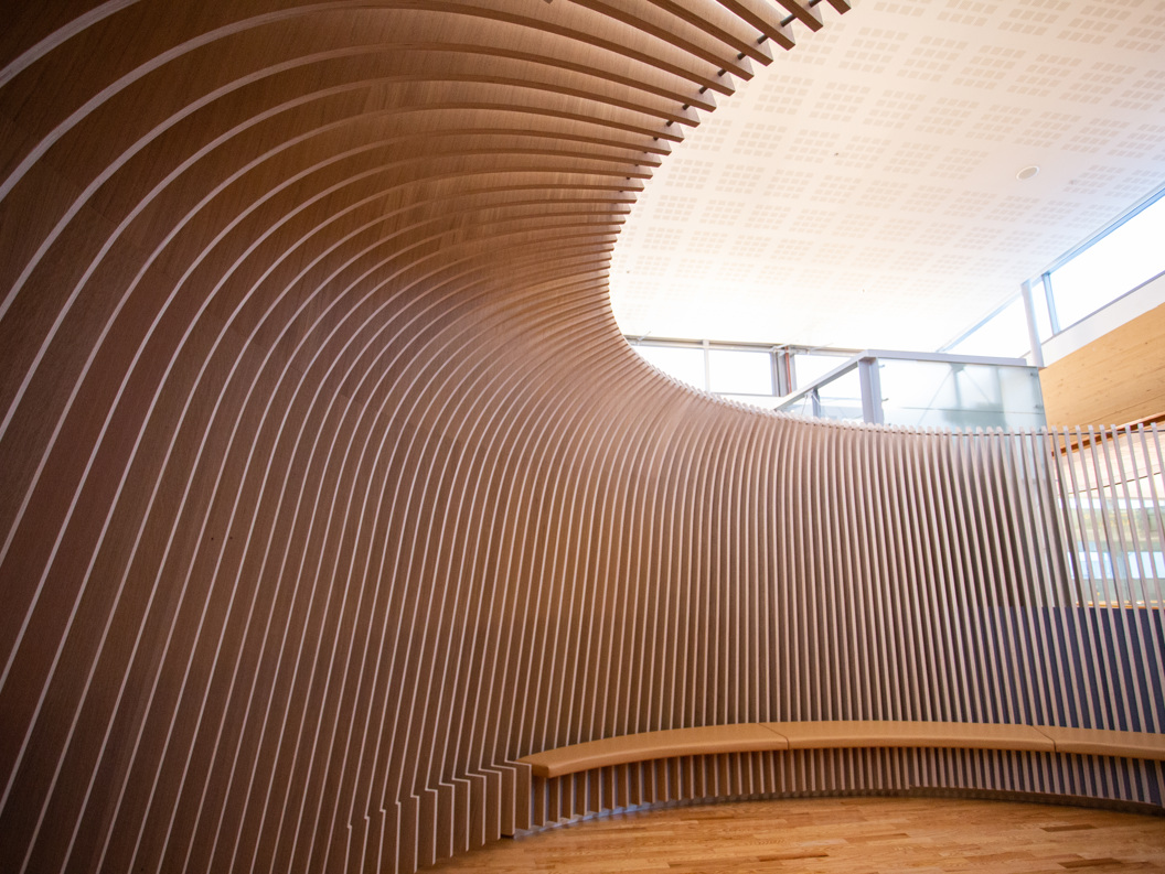 Moderne interiørdesign med bogeformede trepanel og naturleg lys i eit rom for stillheit.