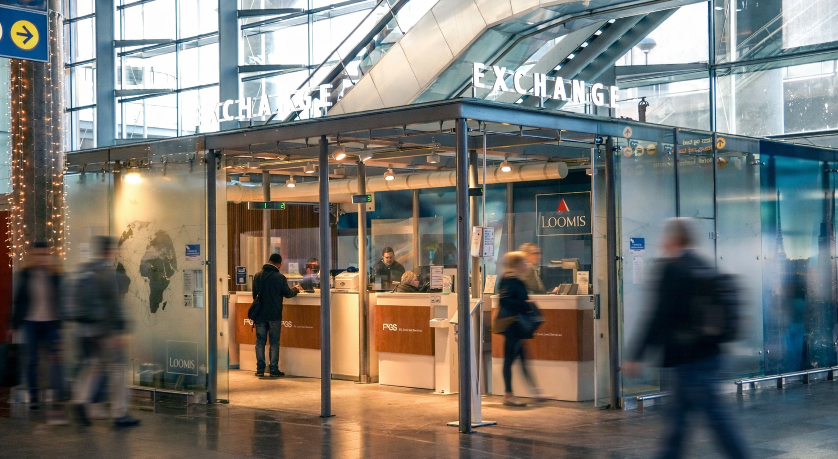 En person som bruker en minibank for utenlandsk valuta på en flyplass, med flere valutamuligheter vist på en skjerm i nærheten, som indikerer internasjonal reise og finansielle transaksjoner