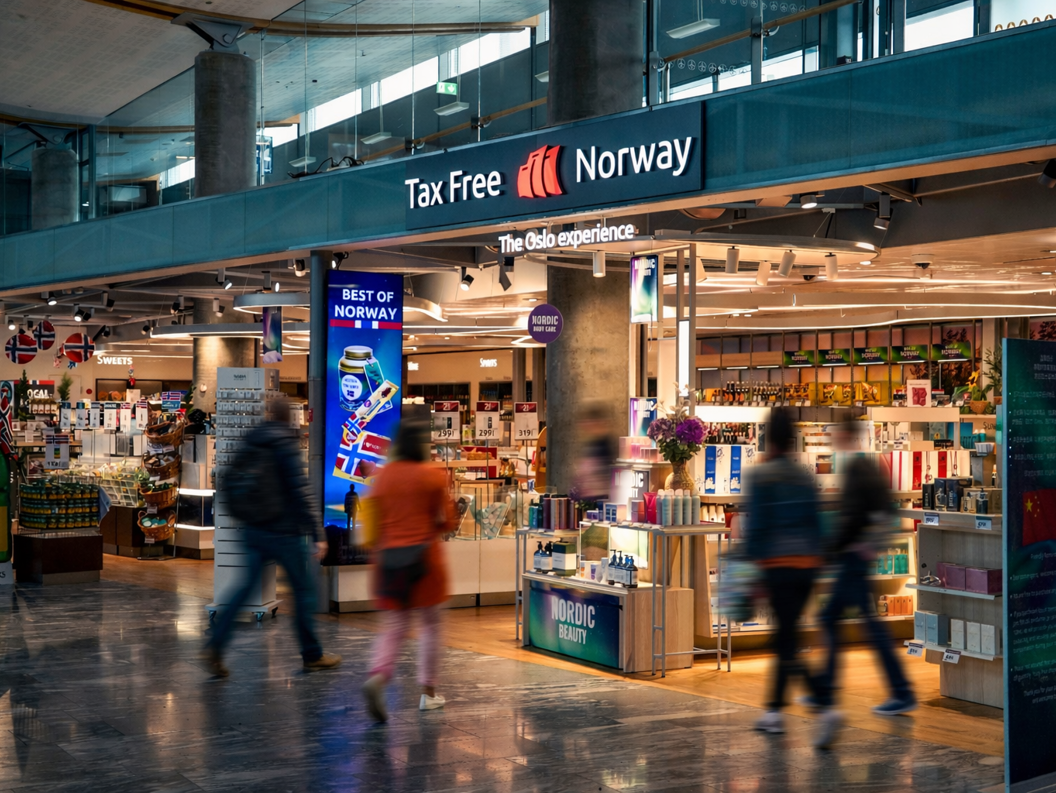 Kvinne handler solbriller i en moderne butikk, iført en svart skinnjakke og smilende mens hun prøver et par solbriller