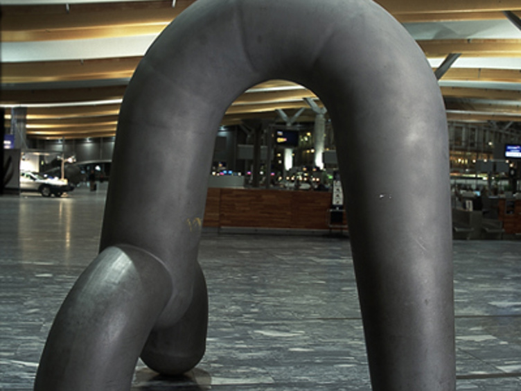 Abstract skulptur på flyplassgulv i moderne passasjerterminal, med trepaneler i taket