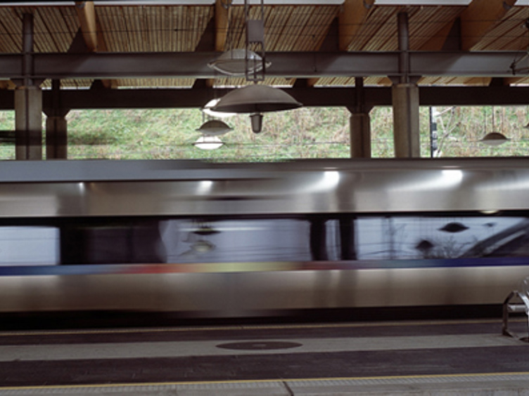 Høyhastighetstog passerer gjennom en moderne togstasjon med tredekor i taket