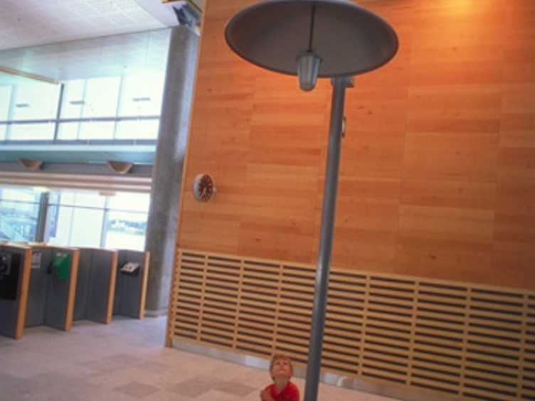 Barn som står under en stor lampe i en moderne innendørssetting