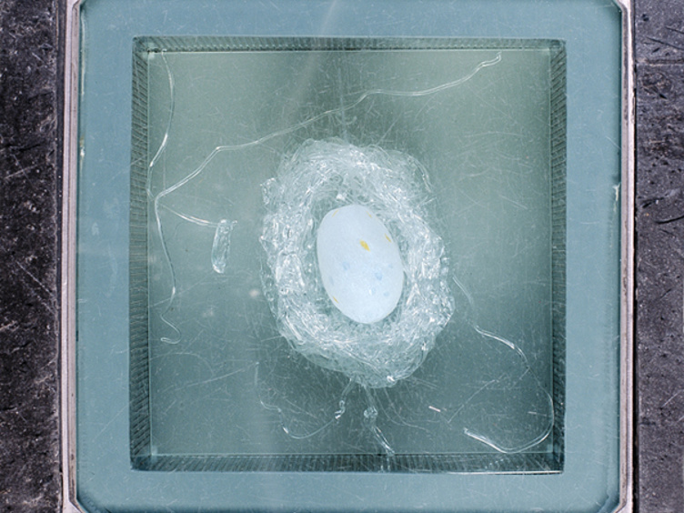 Glassgulv med tydelig sprekkdannelse og hvitt objekt, muligens et egg, i sentrum