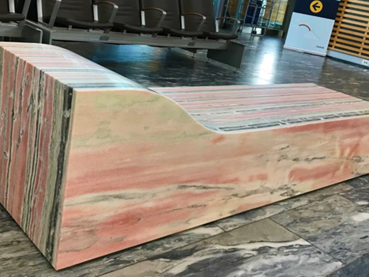 Fargerik benk laget av gamle skateboard, plassert i en moderne ventesone med marmorgulv og stoler i bakgrunnen
