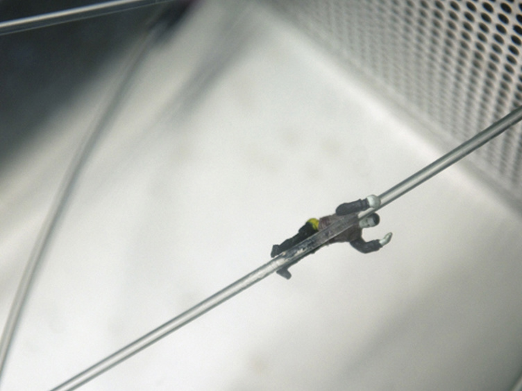 Liten figur som balanserer på metalltråd, moderne kunstinstallasjon med fokus på detaljer og perspektiv